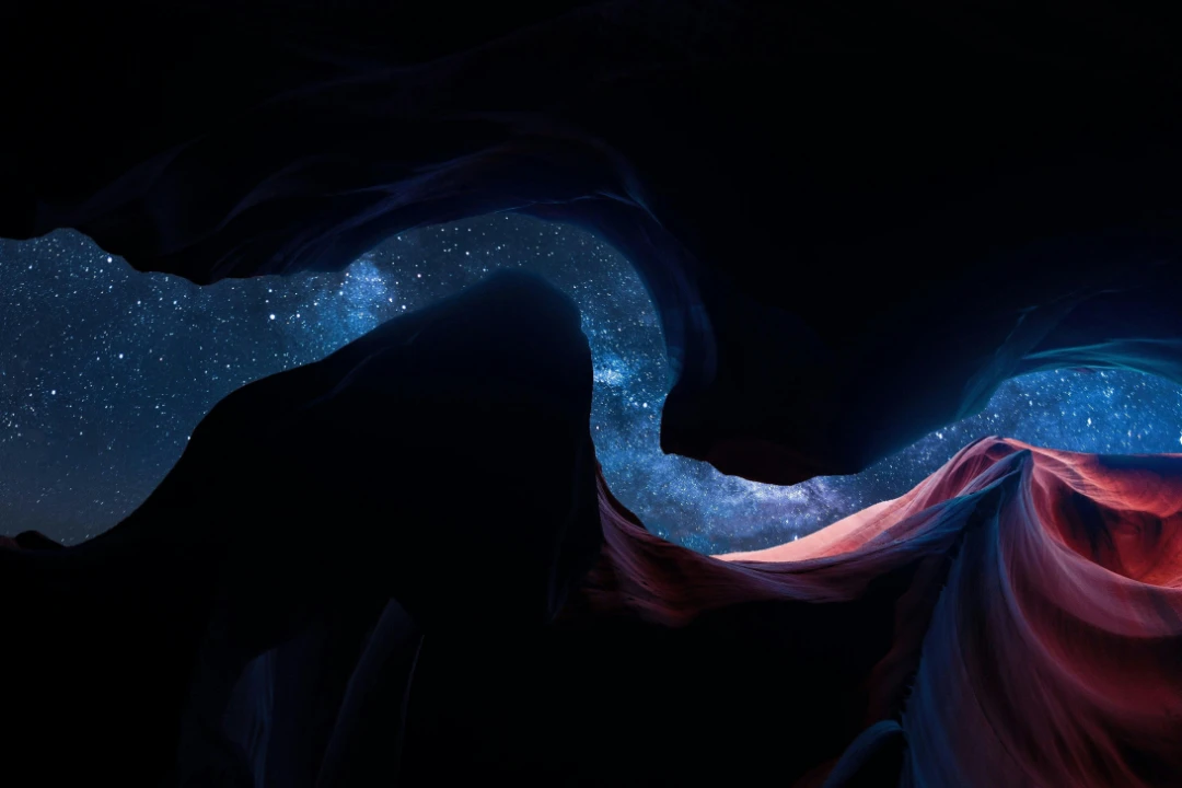 a night time view of stars in the sky between a chasm in a canyon