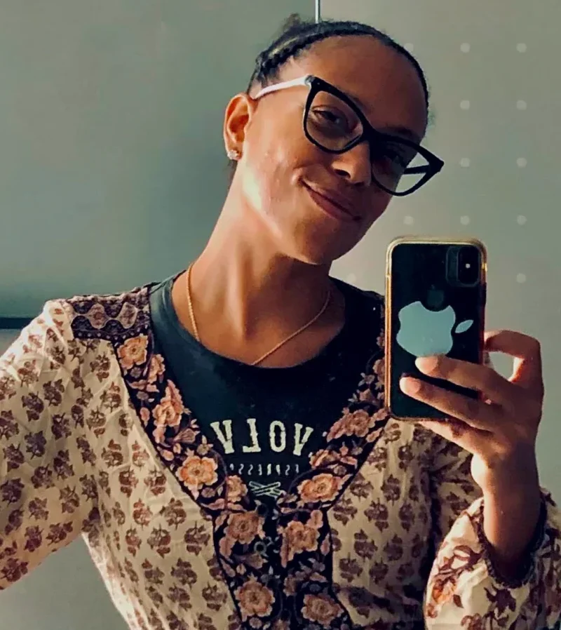 A woman in a brown patterned dress takes a mirror selfie for social media dopamine points before she writes a blog about building confidence