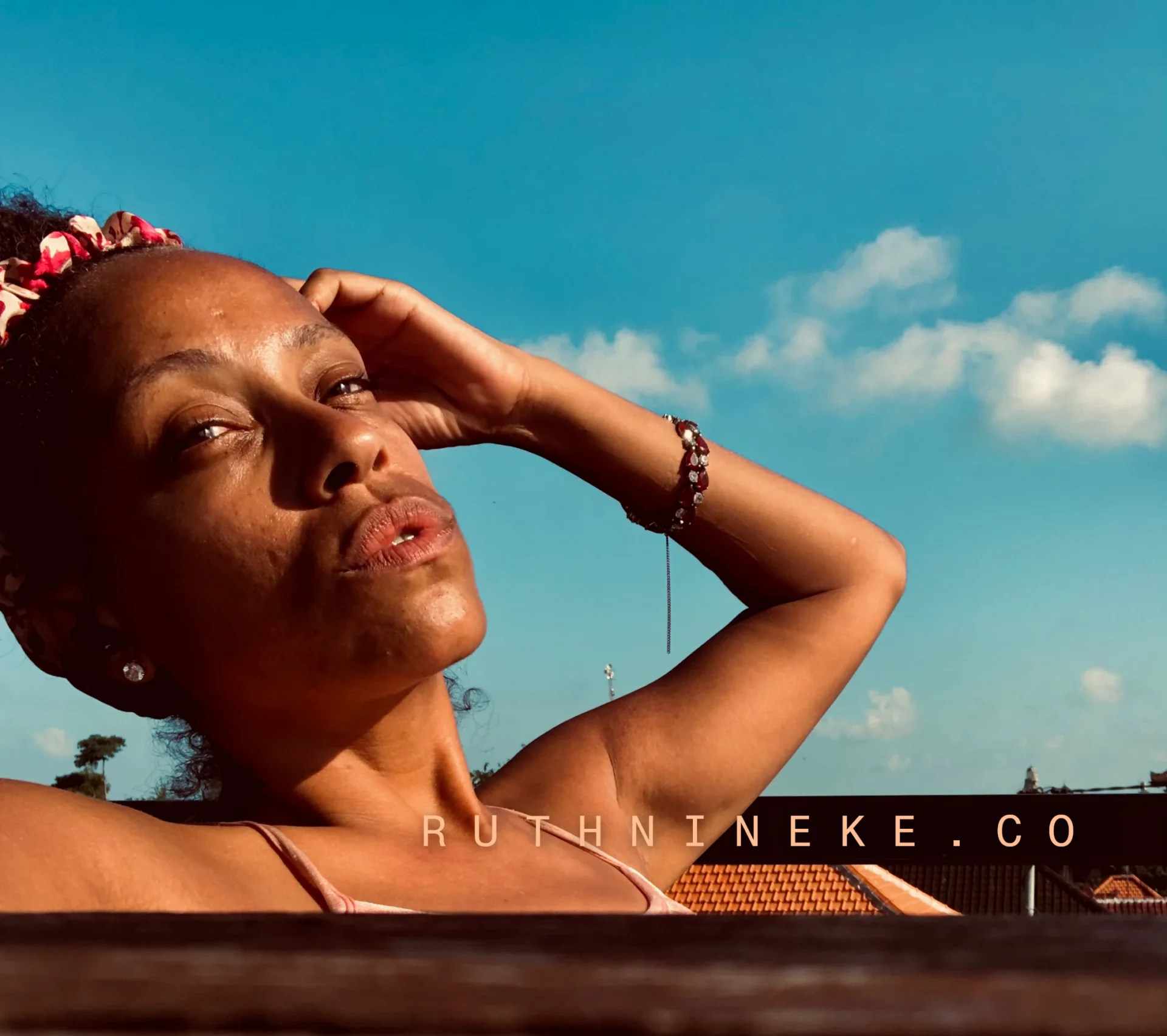 A woman (Ruth Nineke) on a rooftop with her hand beside her head.